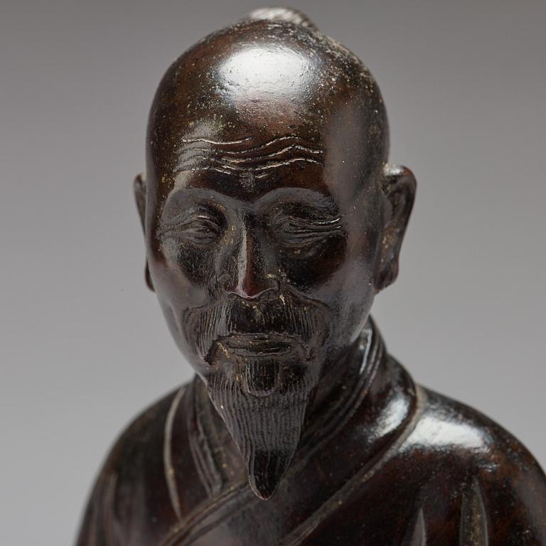 A bronze sculpture of a seated scholar with books, Qing dynasty (1644-1912).