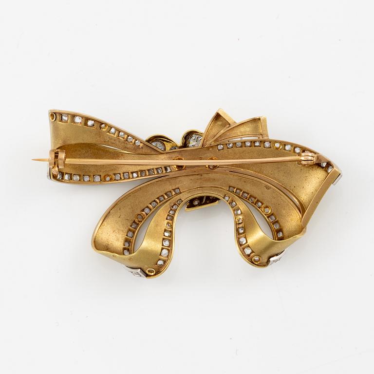 Bow brooch in 18K gold and platinum set with round brilliant, eight-cut, and rose-cut diamonds.