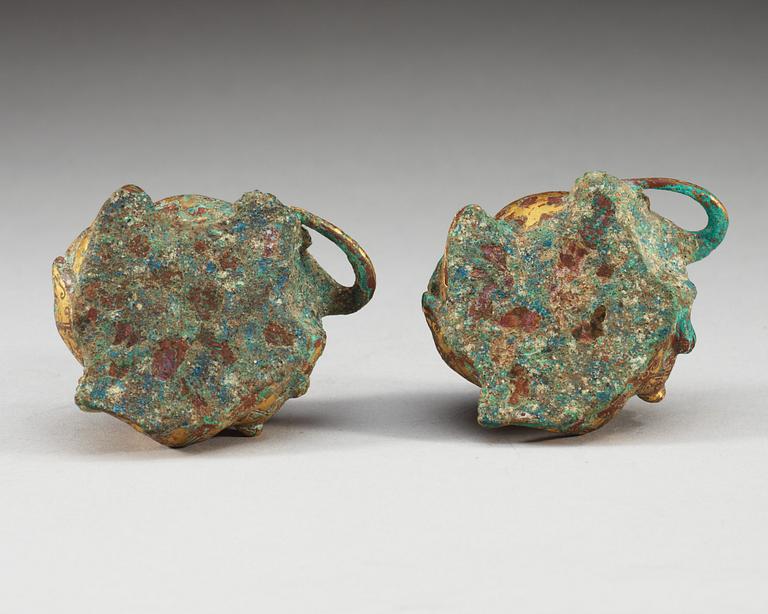 A pair of gilt bronze archaistic weights.