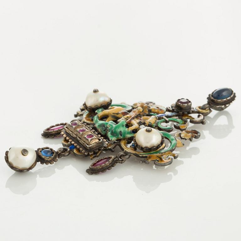 A brooch/pendant in enamelled silver set with pearls and rubies and most likely sapphires.