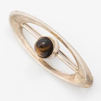 Four silver jewellery pieces: three brooches and a pair of cufflinks. With rose quartz and tiger’s eye. Finnish designers.