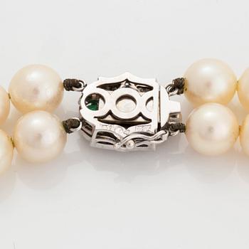 A two strand cultured pearl necklace clasp in 18K white gold set with a faceted emerald.