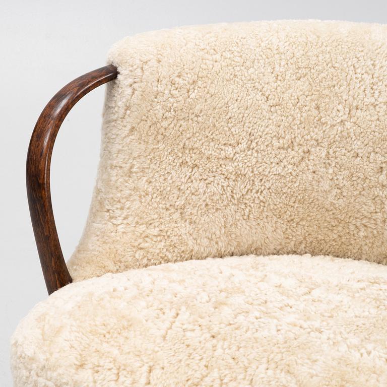 A curved sofa attributed to Viggo Boesen with new sheepskin upholstery and stained beech tree armrests.