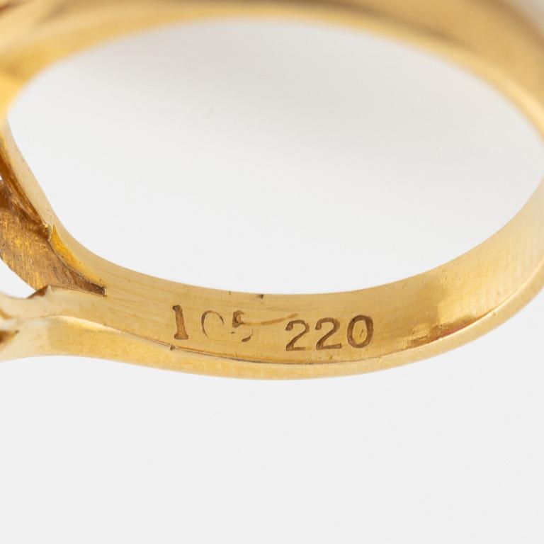 An 18K gold ring set with a cabochon-cut ruby and round brilliant-cut diamonds.