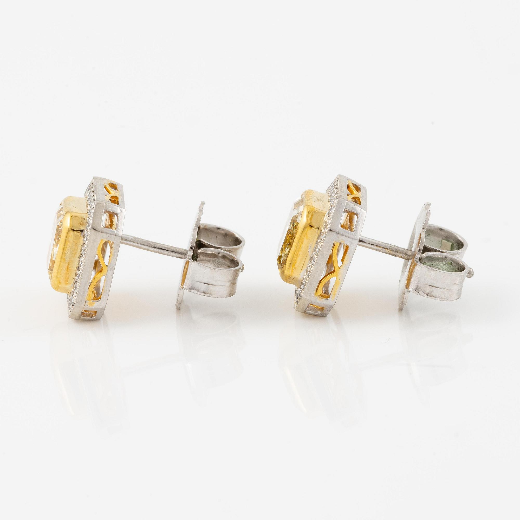 A pair of platinum and gold earrings with two radiant-cut yellow diamonds.