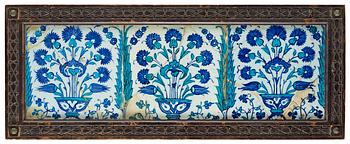 243A. TILES, 3 pieces, glazed pottery. Iznik, Turkey, 17th century A.D. The mid tile 25,5 X 25,5 cm, the two others 24,5 X 24,5 cm each. Later wooden frame 33,5 x 84,5 cm.