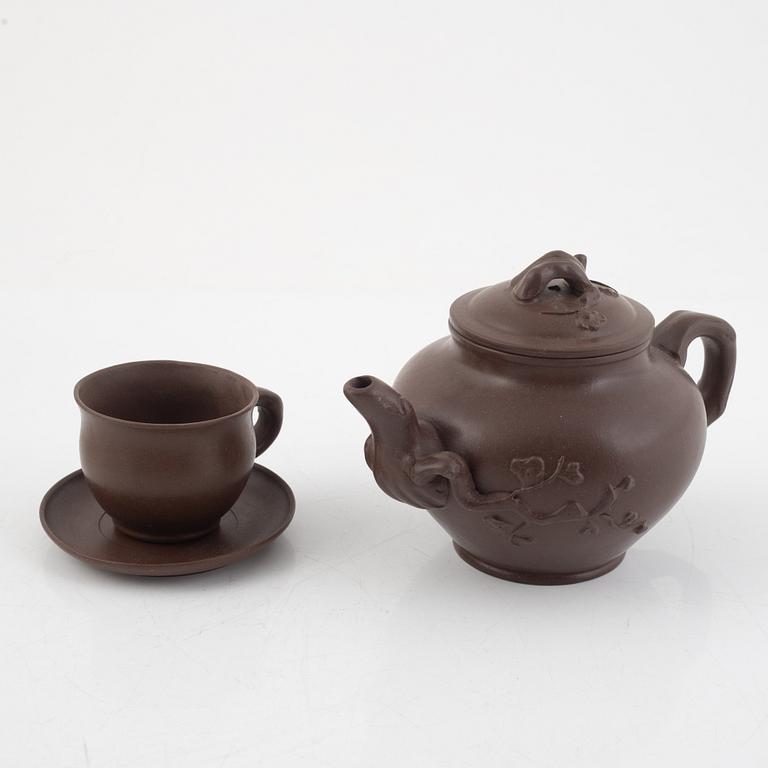 A Chinese yixing teapot with four cups and saucers, 2oth century.