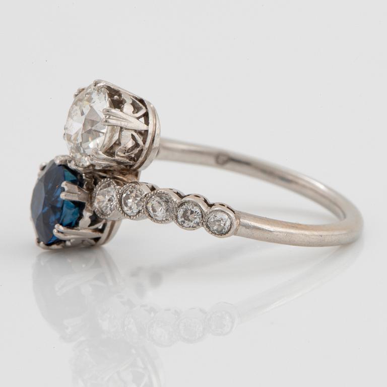 A platinum ring set with old-cut diamonds and a faceted sapphire.