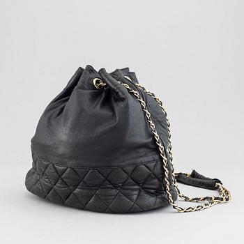 Chanel, a black leather drawstring bag.