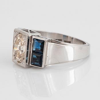 An 18K white gold ring set with an old-cut dimond weight ca 1.50 cts and step-cut sapphires.