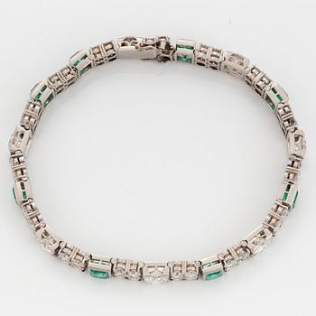 A platinum bracelet set with round brilliant- and old-cut diamonds and faceted emeralds.