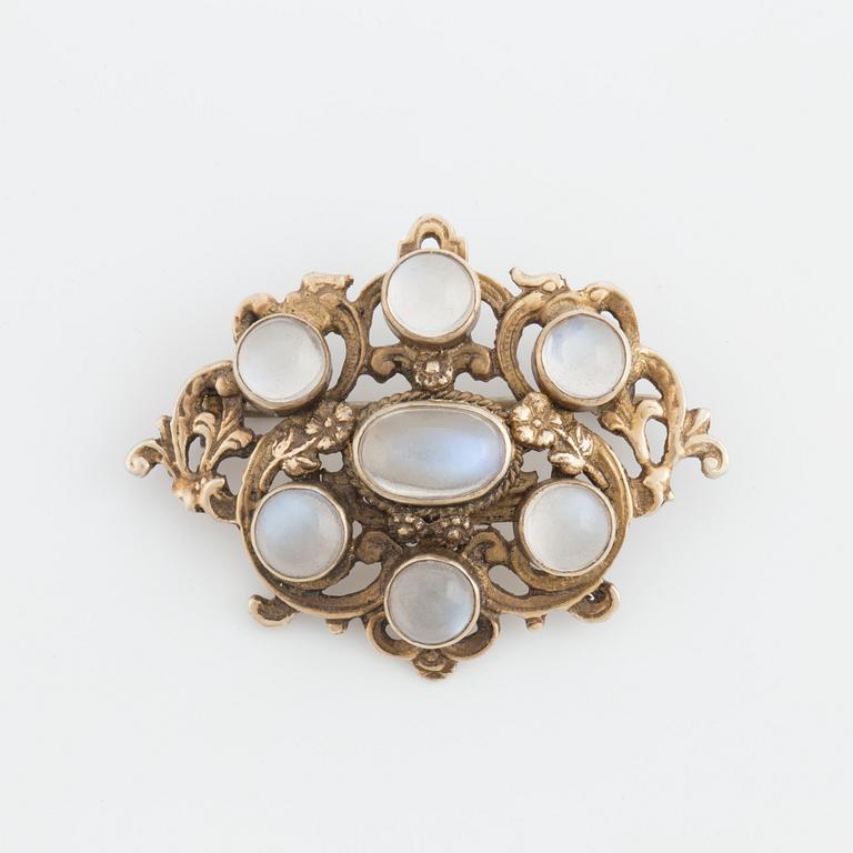 A brooch set with cabochon-cut moonstones.