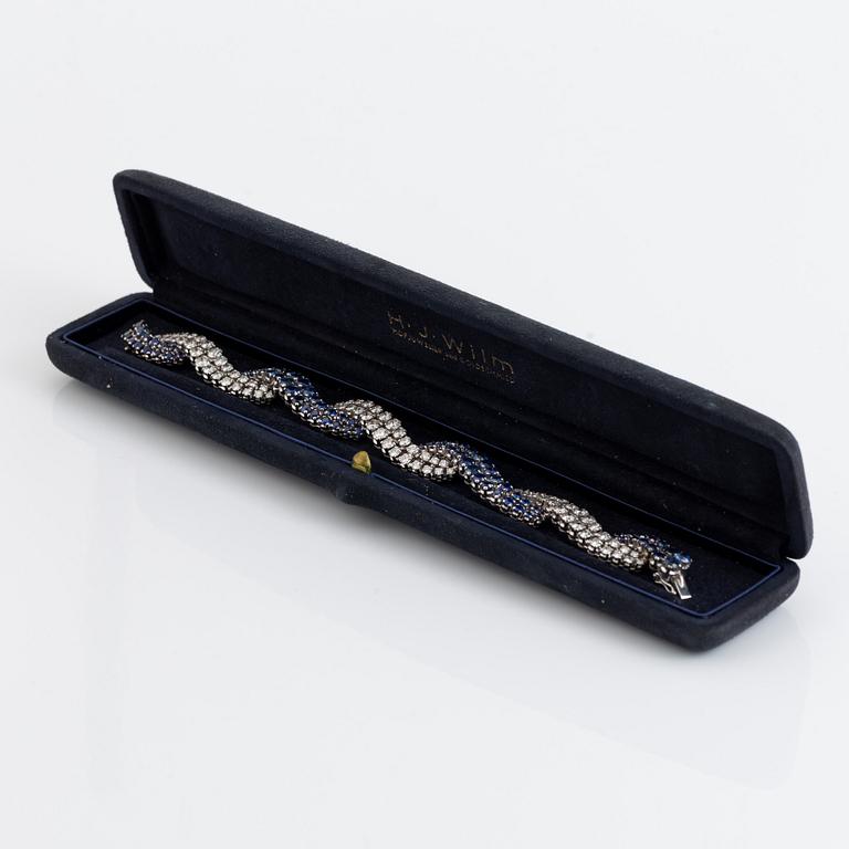 An 18K white gold bracelet set with round brilliant-cut diamonds and sapphires.