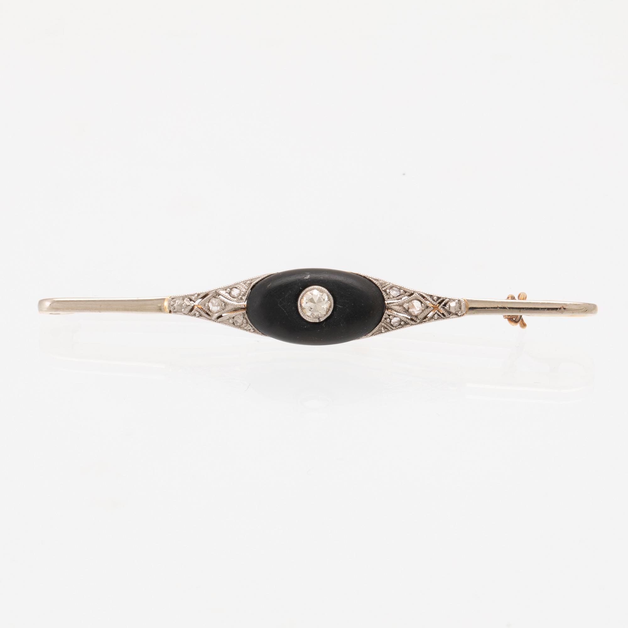 A 14K white and red gold brooch set with round brilliant-cut and rose-cut diamonds and a black stone.