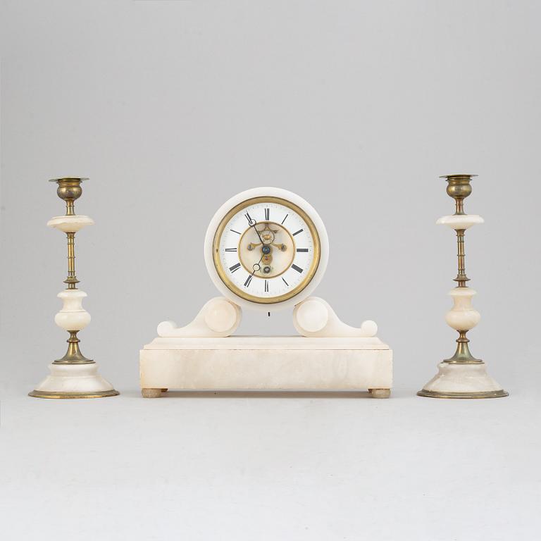 An alabaster mantle clock and pair of candlesticks, circa 1900.