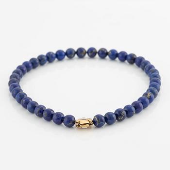 An Ole Lynggaard clasp in 18K gold with round brilliant-cut diamonds and a lapis lazuli necklace.