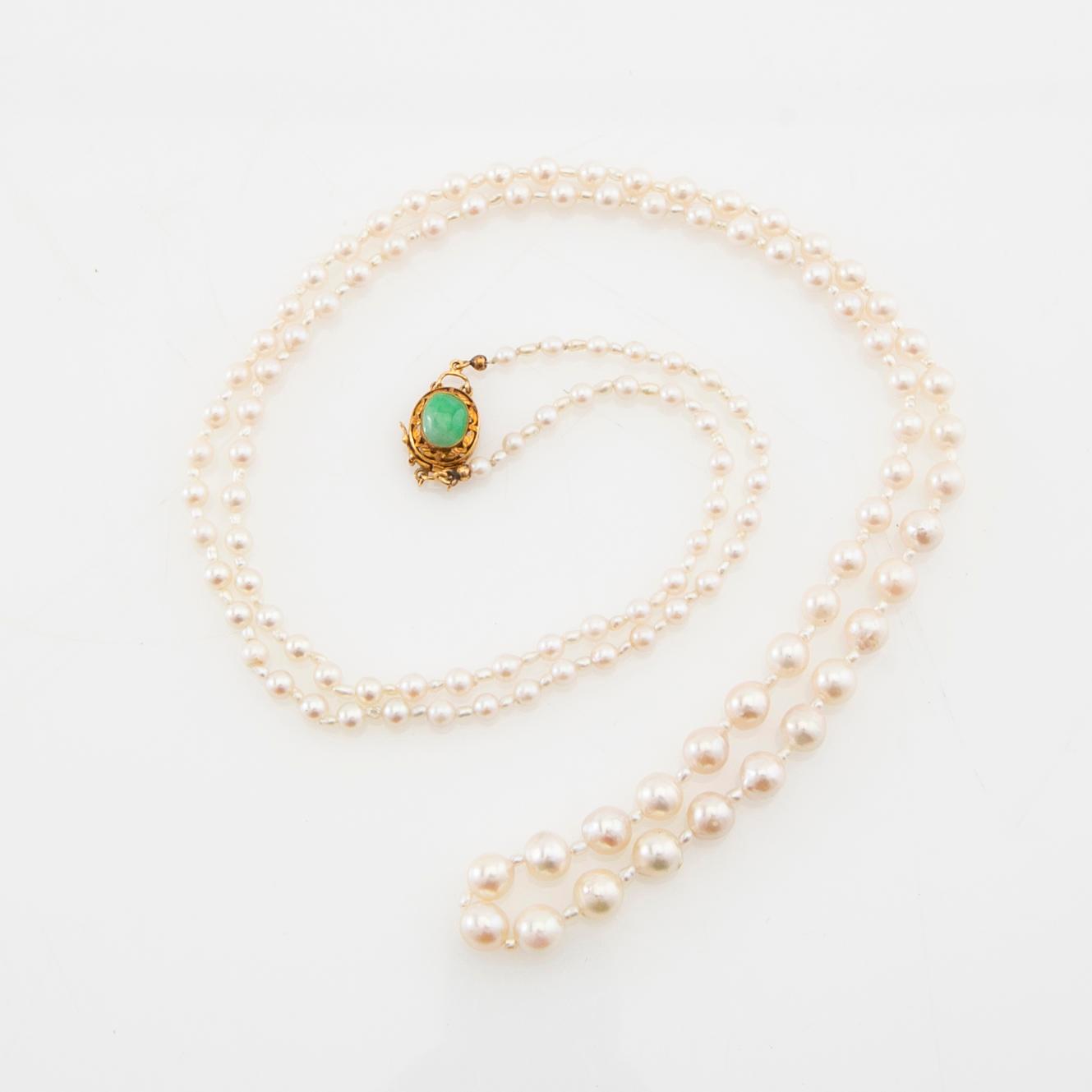 Necklace of cultured pearls with a clasp of 18K gold and cabochon-cut green stone.