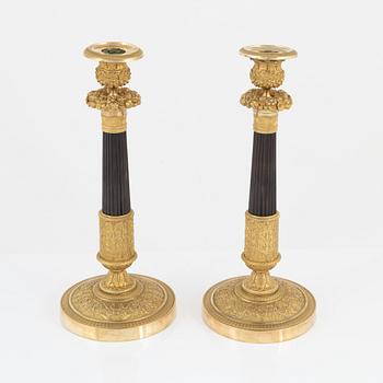 A pair of French Empire ormolu and patinated bronze candlesticks, early 19th century.
