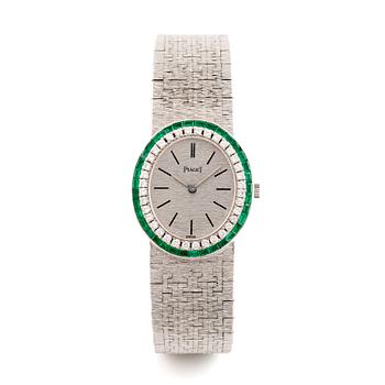 A Piaget 18K white gold wrist watch set with round brilliant-cut diamonds and step-cut emeralds.