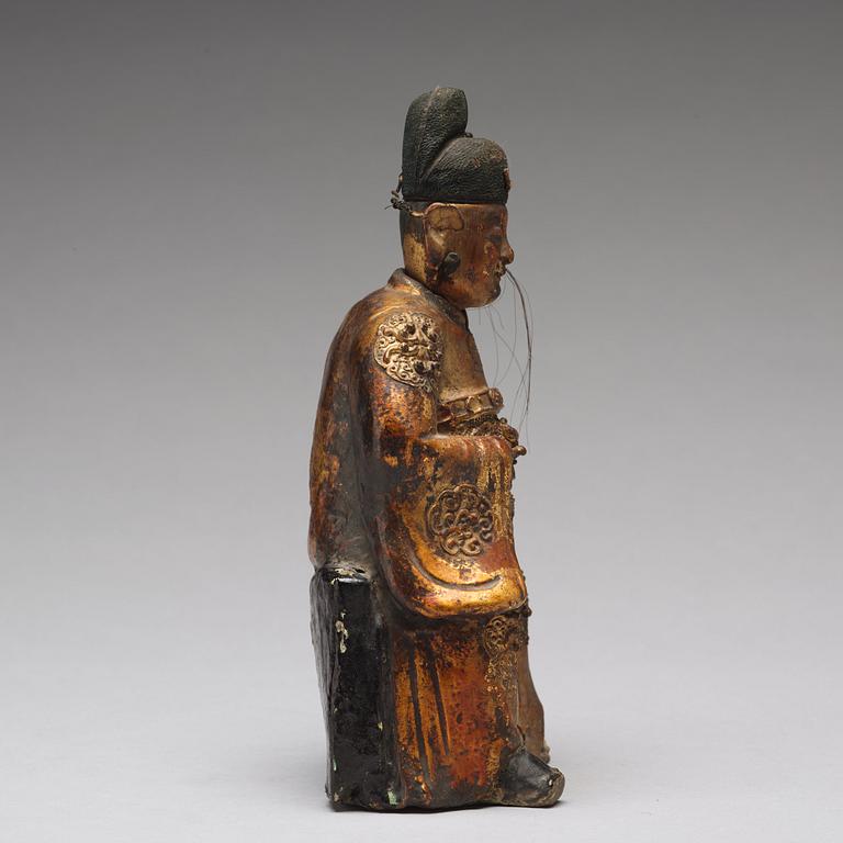 A lacquered and gilt ceramic sculpture of a deity, Ming dynasty (1368-1644).