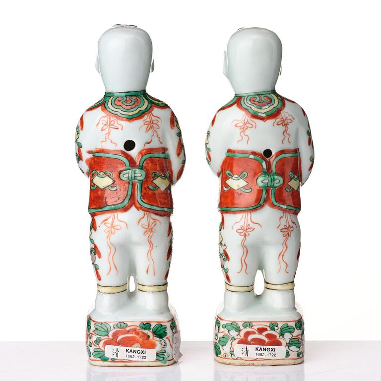 A pair of wucai decorated porcelain figurines of boys with flowers, Qing dynasty, Kangxi (1662-1722).