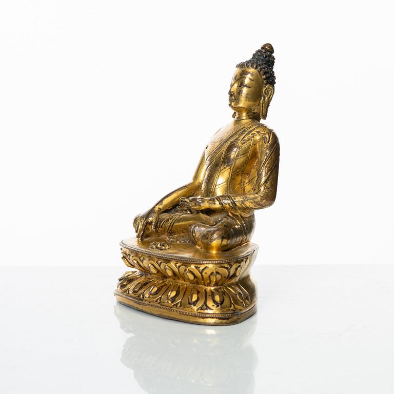 A gilt copper-alloy figure of Aksobhya Buddha, 14th/15th century, Tibet or Nepal.