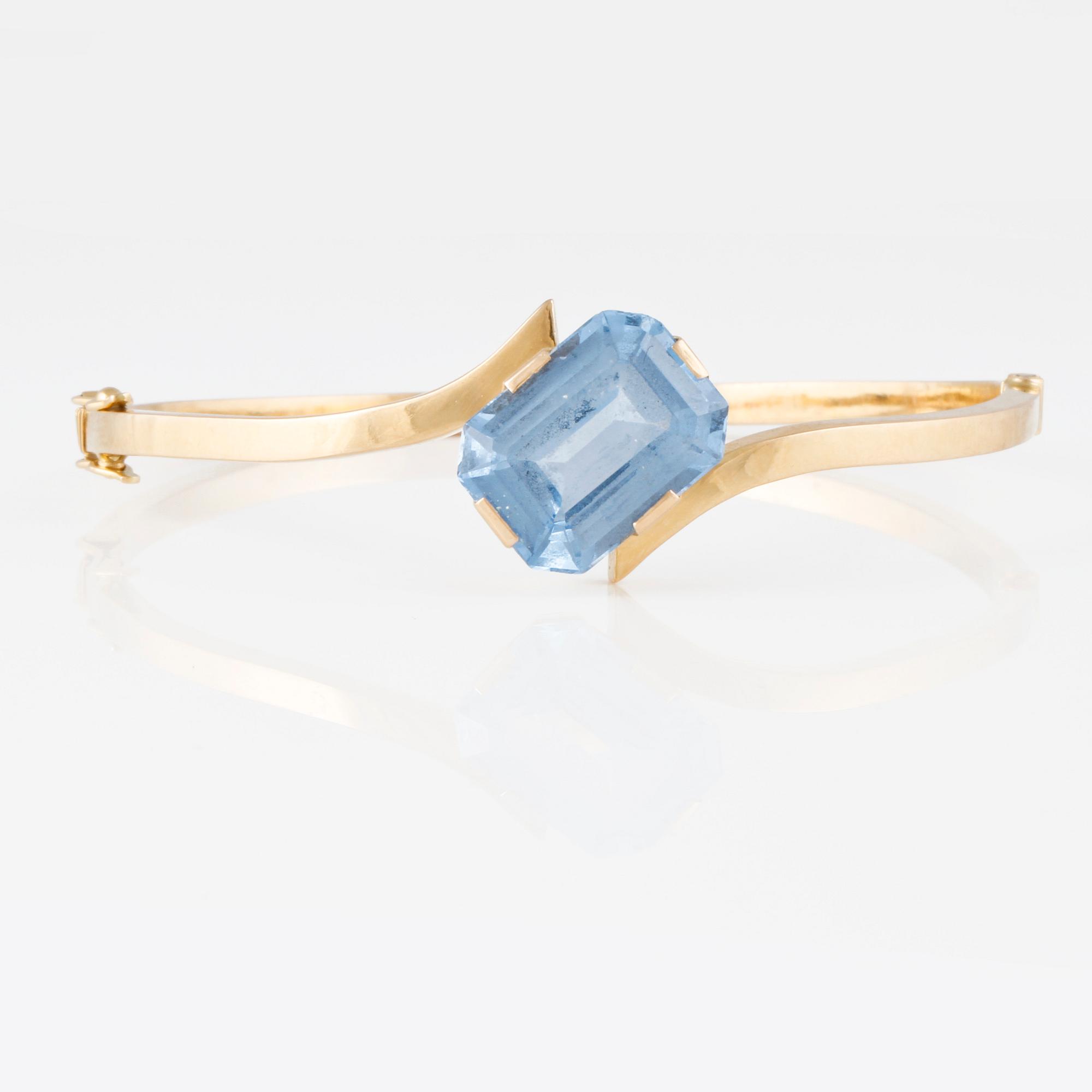 ARMRING, 18K guld med fasettslipad syntetisk blå spinell, Svenskt Guldsmide, Stockholm, 1956. Vikt 9,8 gram.
