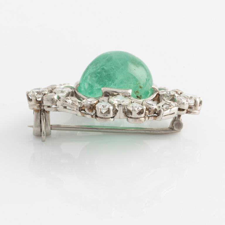 A platinum brooch with a cabochon-cut emerald.