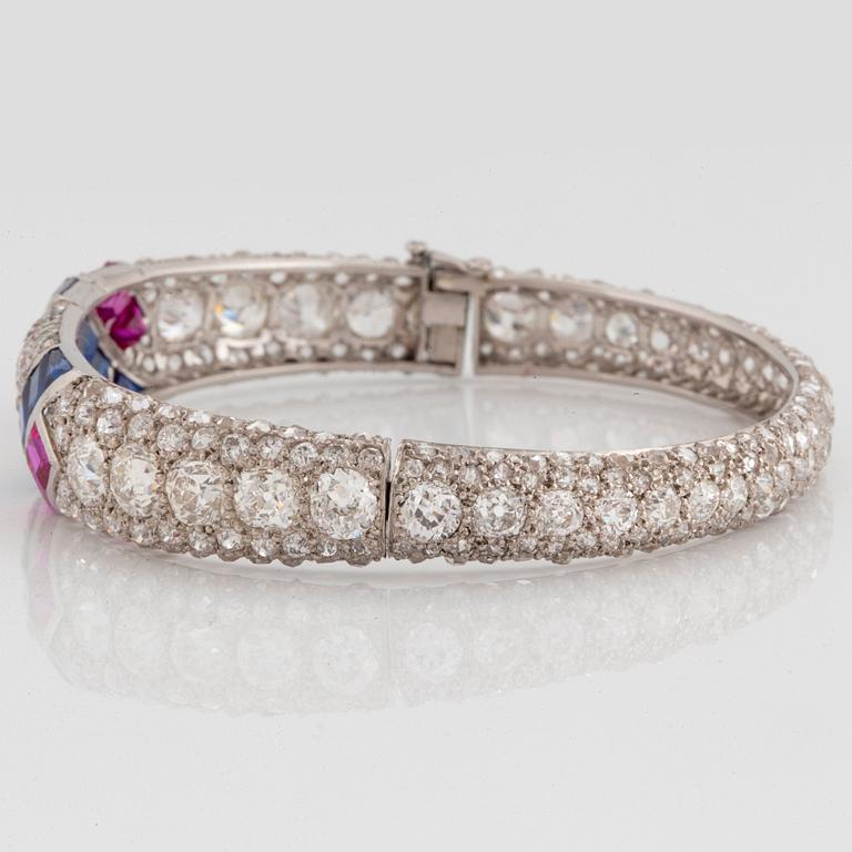 A platinum bangle set with old- and rose-cut diamonds and faceted sapphires and rubies.