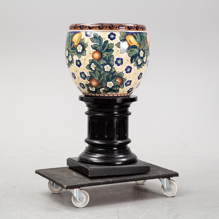 A handpainted faience, urn on wooden pedestal. Aluminia, Denmark. Dated 1910.