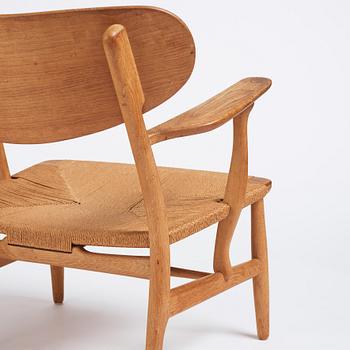 Hans J. Wegner, a pair of "CH 22" oak chairs, Carl Hansen & Son, Odense, Denmark, mid 20th century.