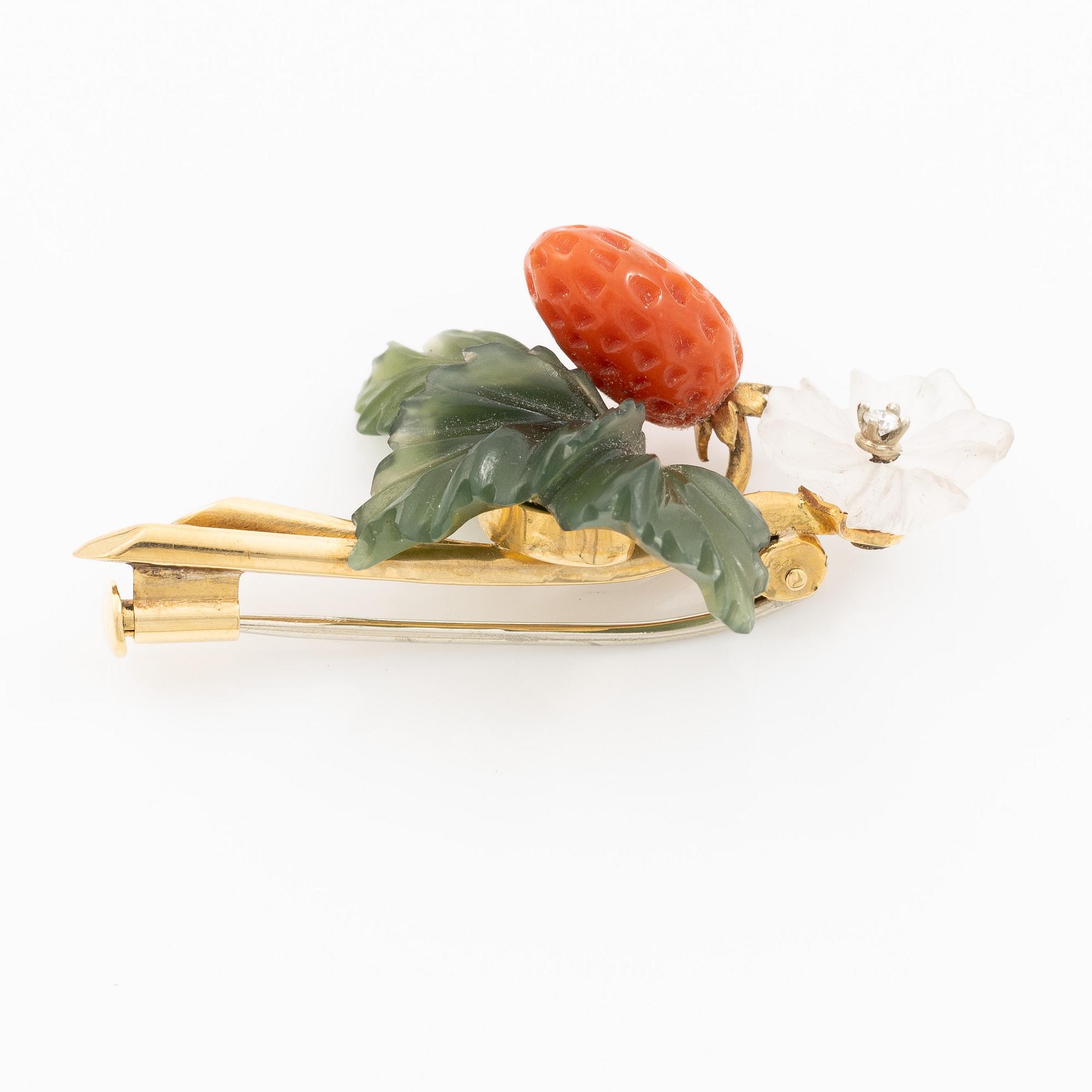 A flower brooch 18K gold with coral, rock crystal, a green stone likely nephrite, and a round brilliant-cut diamond.