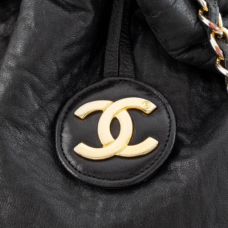 Chanel, a black leather drawstring bag.