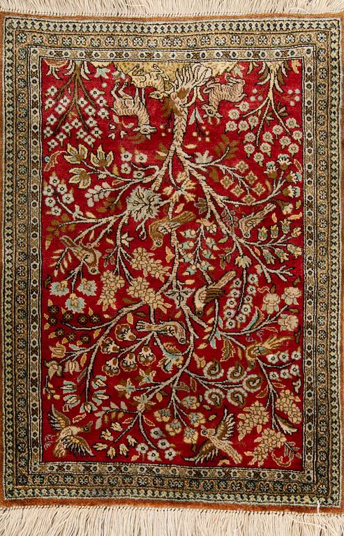 A silk rug from Qum, around 75 x 54 cm.