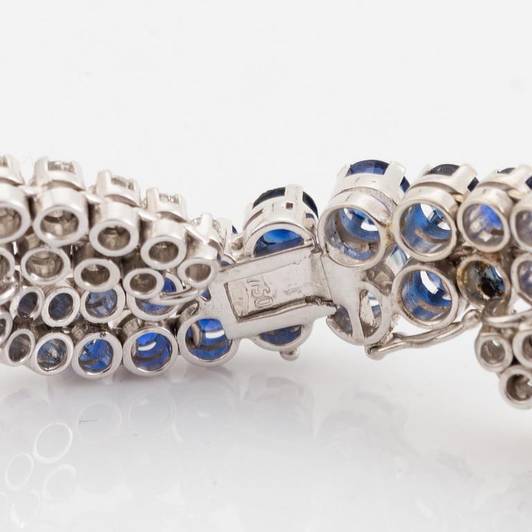 An 18K white gold bracelet set with round brilliant-cut diamonds and sapphires.