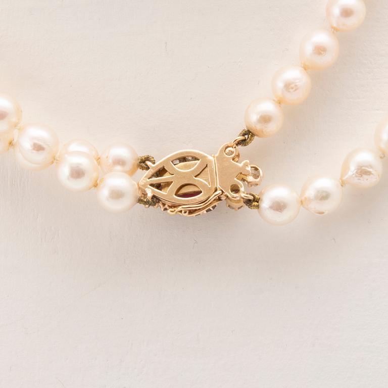 A double-stranded necklace with cultured pearls and an 18K gold clasp with a faceted synthetic ruby and old-cut diamonds.