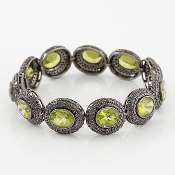 Bracelet in 18K gold with oval peridots and brilliant-cut black diamonds.