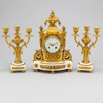 A late 19th century pendulum clock and a pair of candelabras.