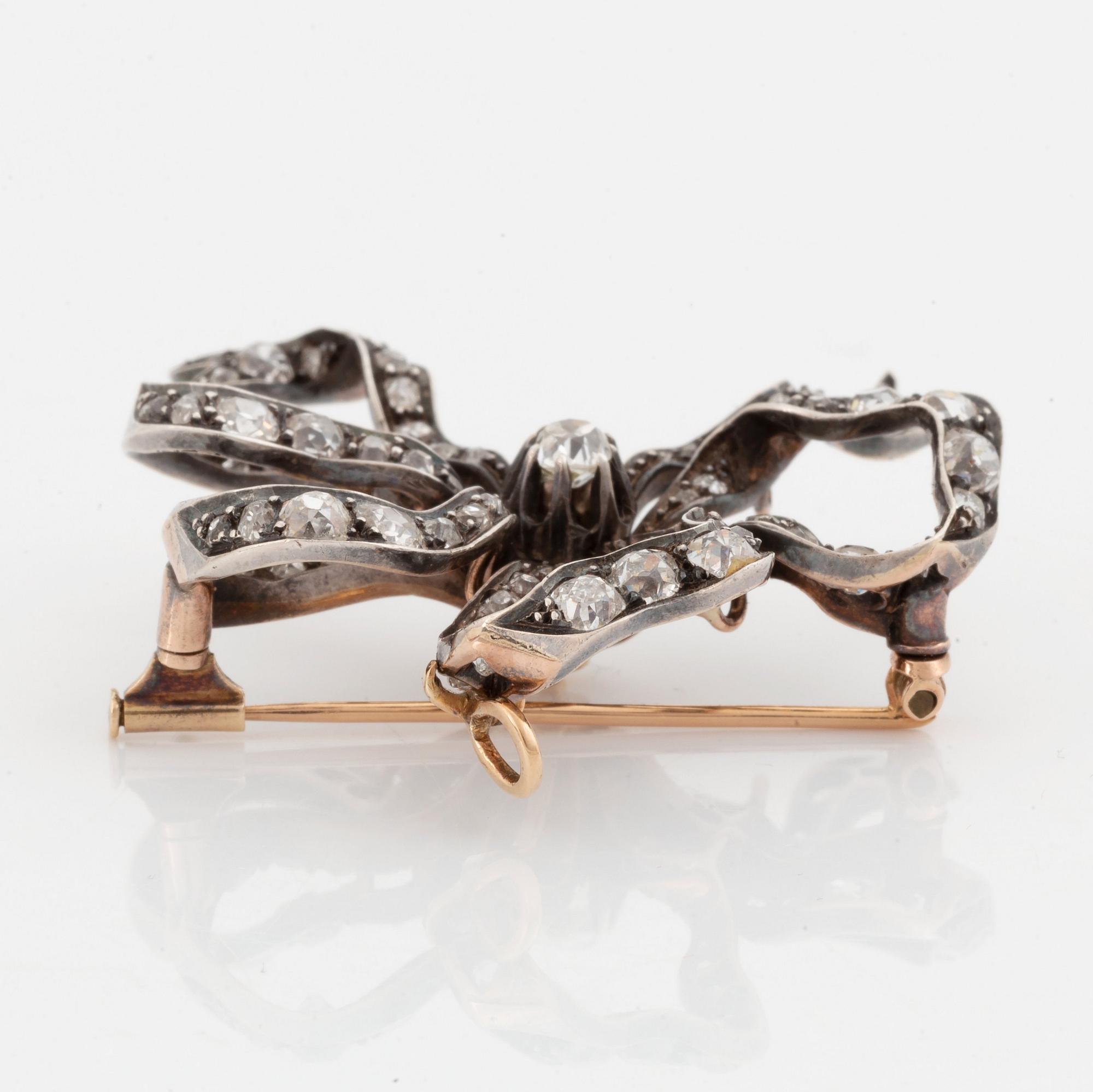 A silver and 14K gold bow brooch/pendant set with old- and rose-cut diamonds.