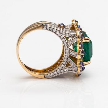 A 14k gold ring with an emerald ca. 6.39 ct, tanzanites and diamonds ca. 1.25 ct in total.