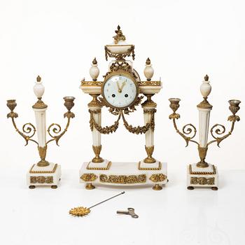A Louis XVI-style mantle clock and a pair of candelabras. Early 20th century.