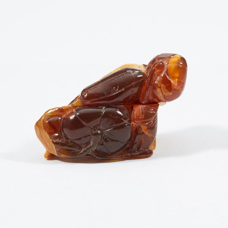 A carved amber figure/pendant of two squirrels sitting on some fruit, early 20th Century.