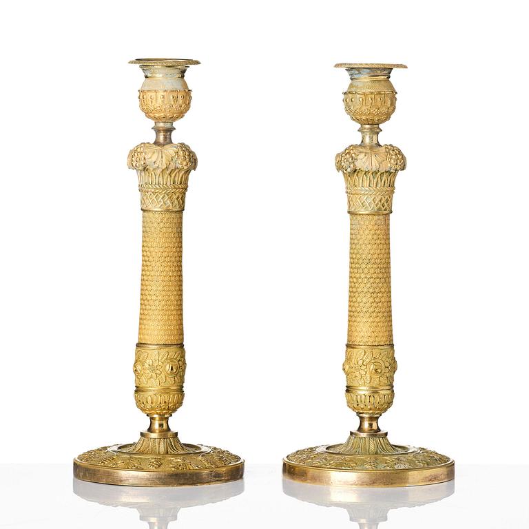 A pair of French Empire ormolu candlesticks, ca 1820's.