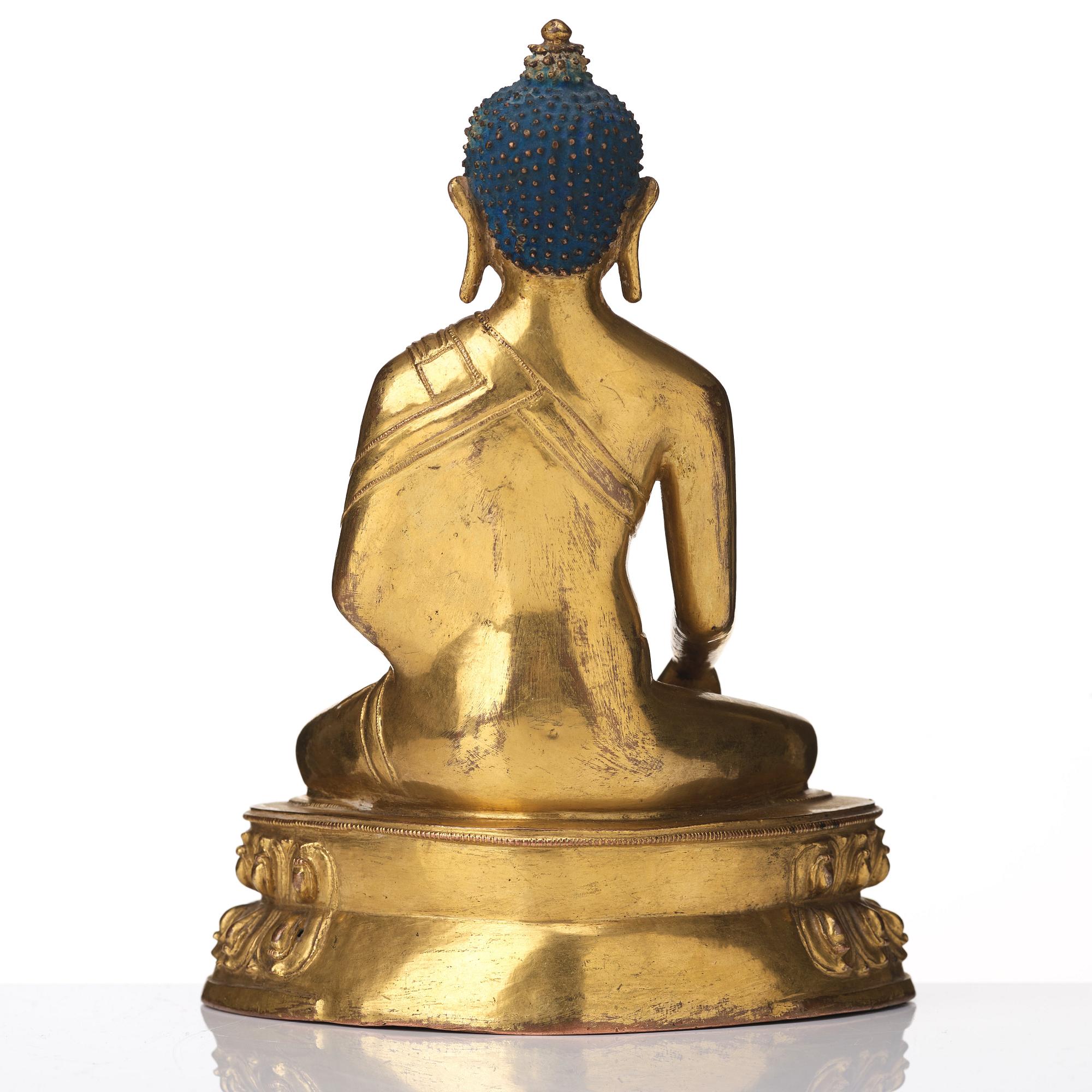 A gilt copper alloy figure of Akhsobya buddha, Tibet, 15th Century.