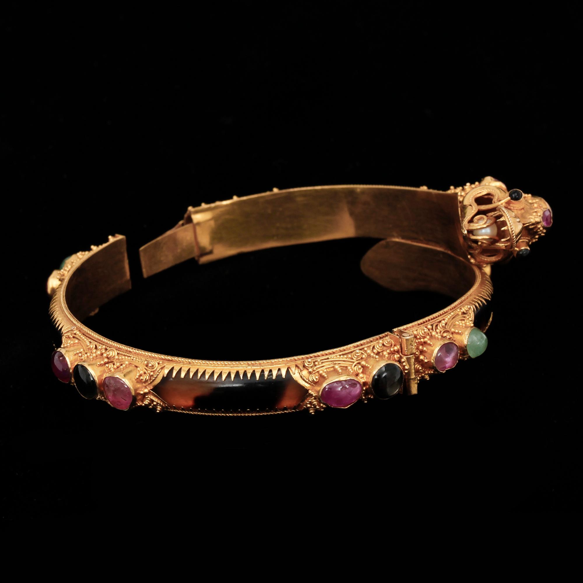 ARMBAND, 22k guld med flertal trumlade ädelstenar, bla. rubiner och smaragder. Vikt 26,9 g.