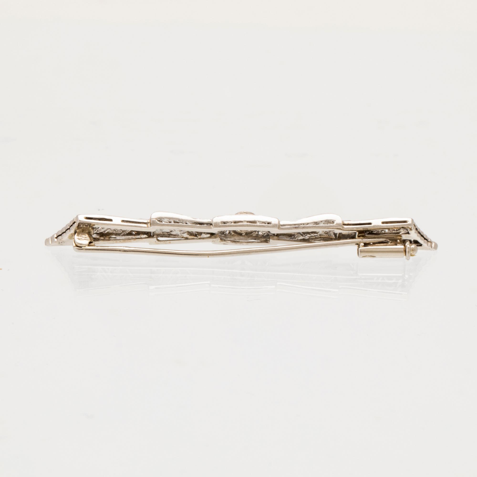 Brosch 18K vitguld med en rund briljantslipad diamant samt rosenslipade diamanter.