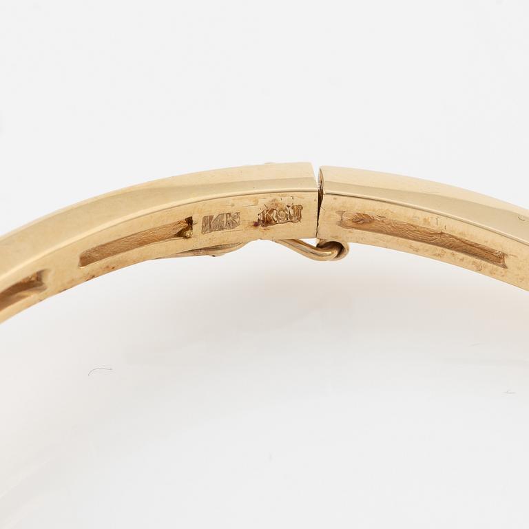 A bangle in 14K gold with round brilliant-cut diamonds.