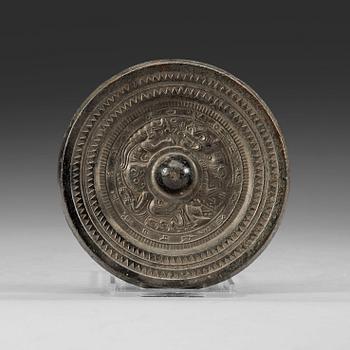 A bronze mirror decorated with characters a stylized dragon and tiger, Eastern Han dynasty (25-220).