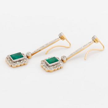A pair of platinum and gold earrings set with step-cut emeralds and old-cut diamonds.