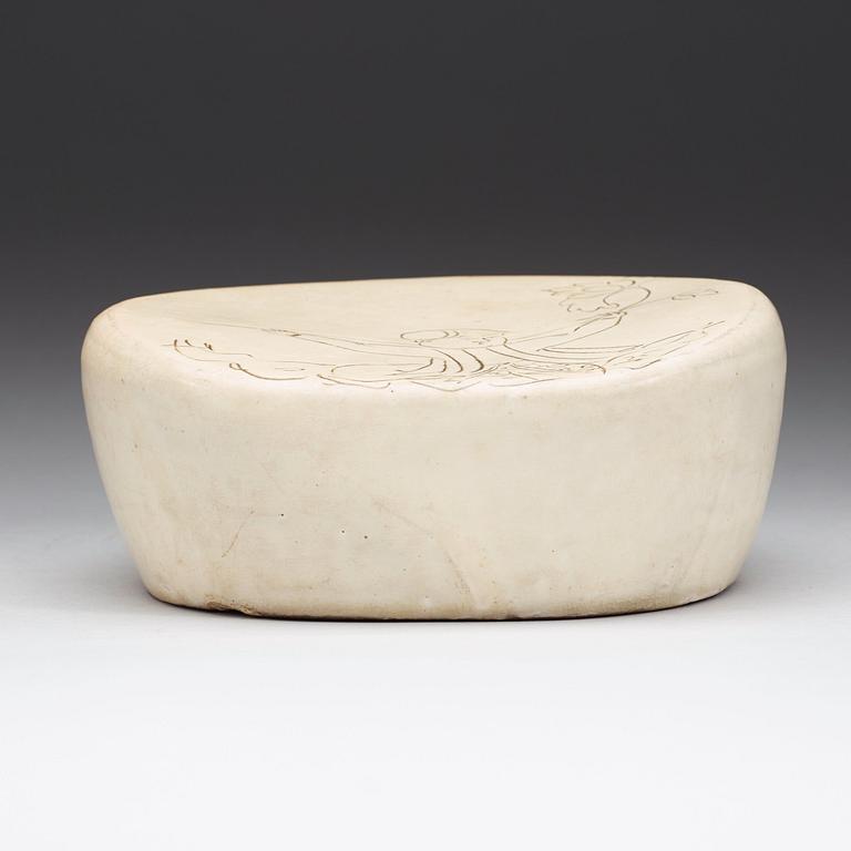 A potted white glazed pillow with incised decor of a boy, presumably Liao or Song Dynasty (907-1279).